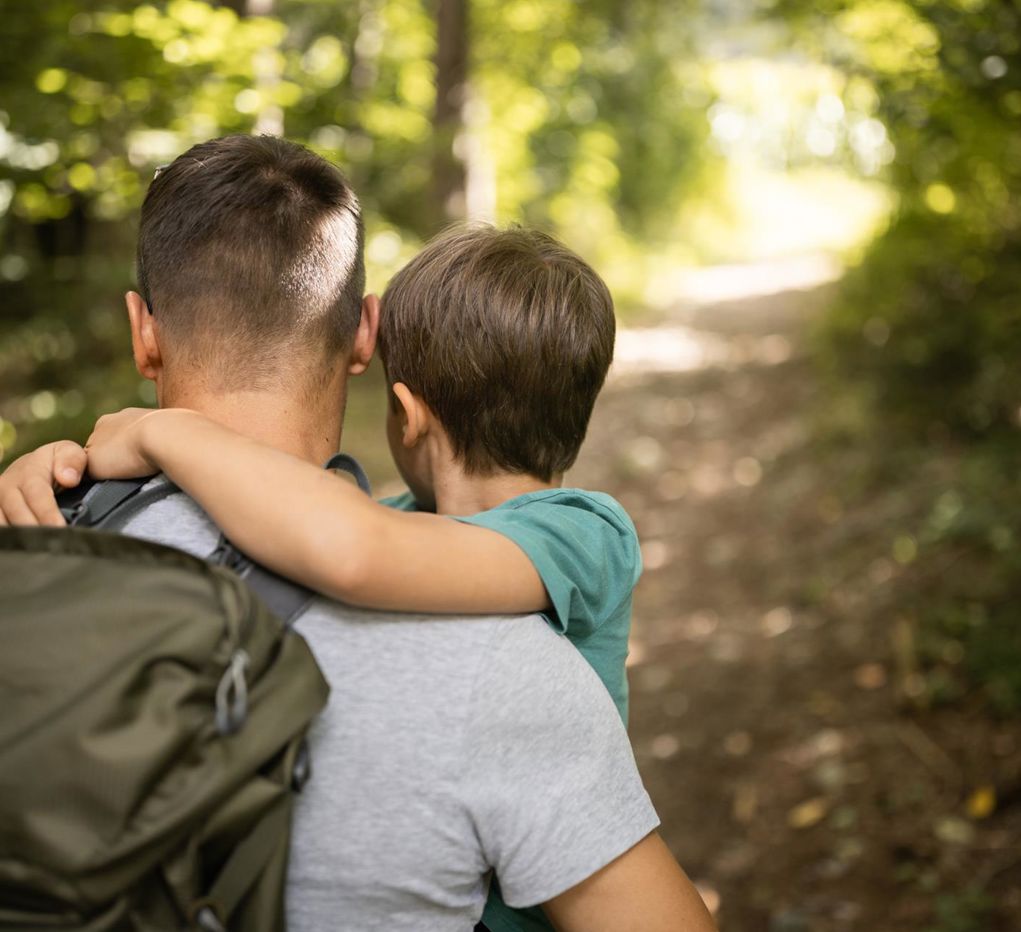 A man and a child are hiking in the forest