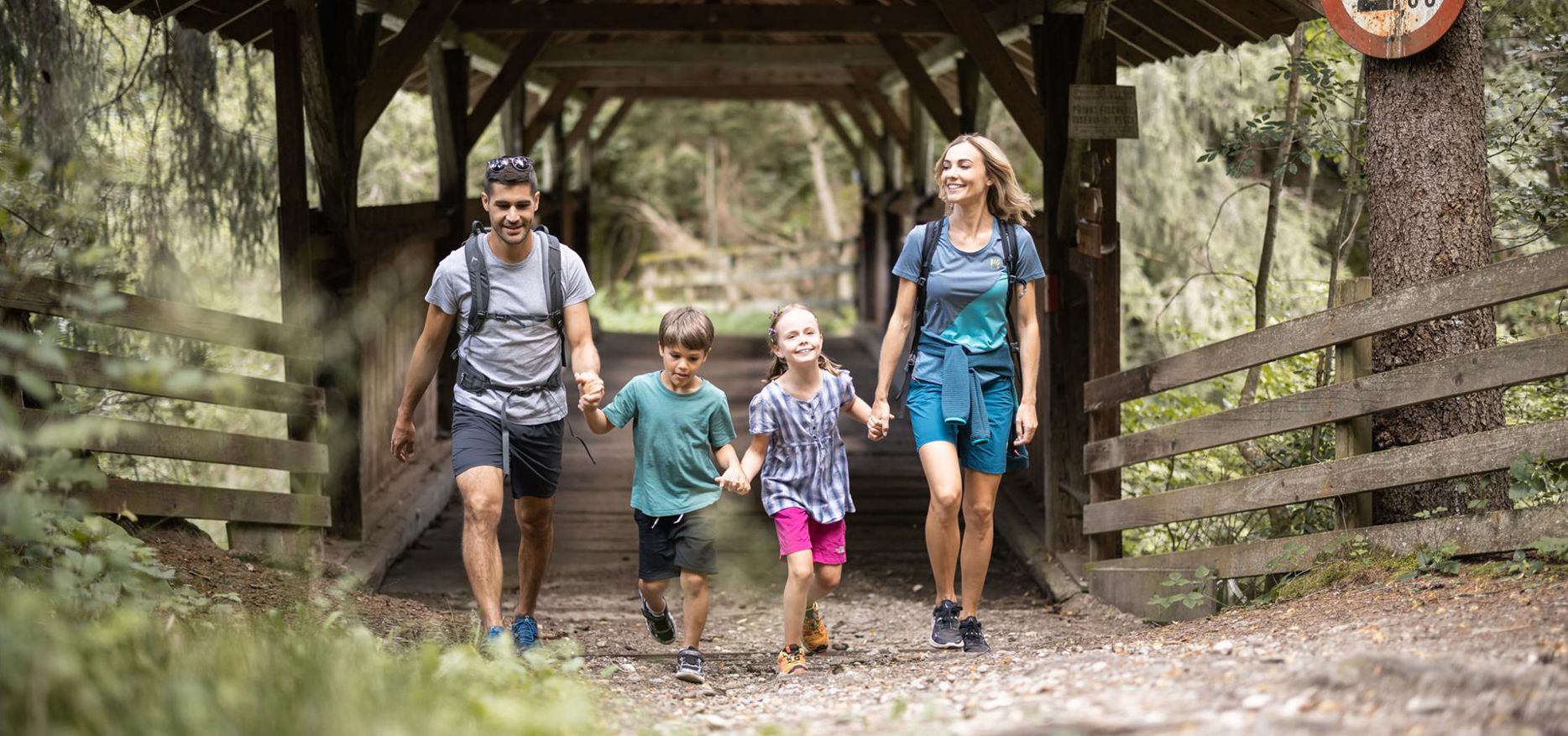 A family is hiking across the bridge in the Rienz Gorge