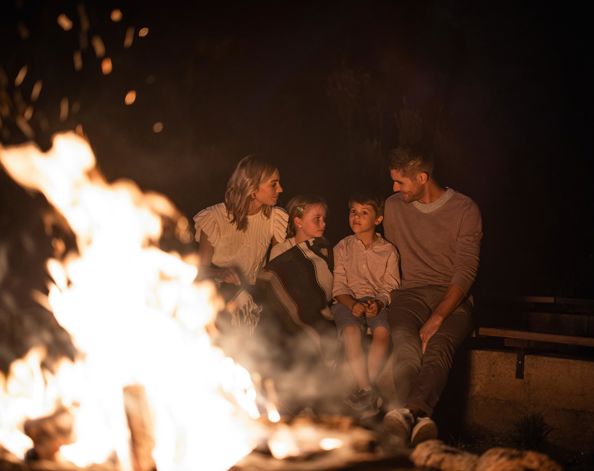 A family is sitting in front of a campfire