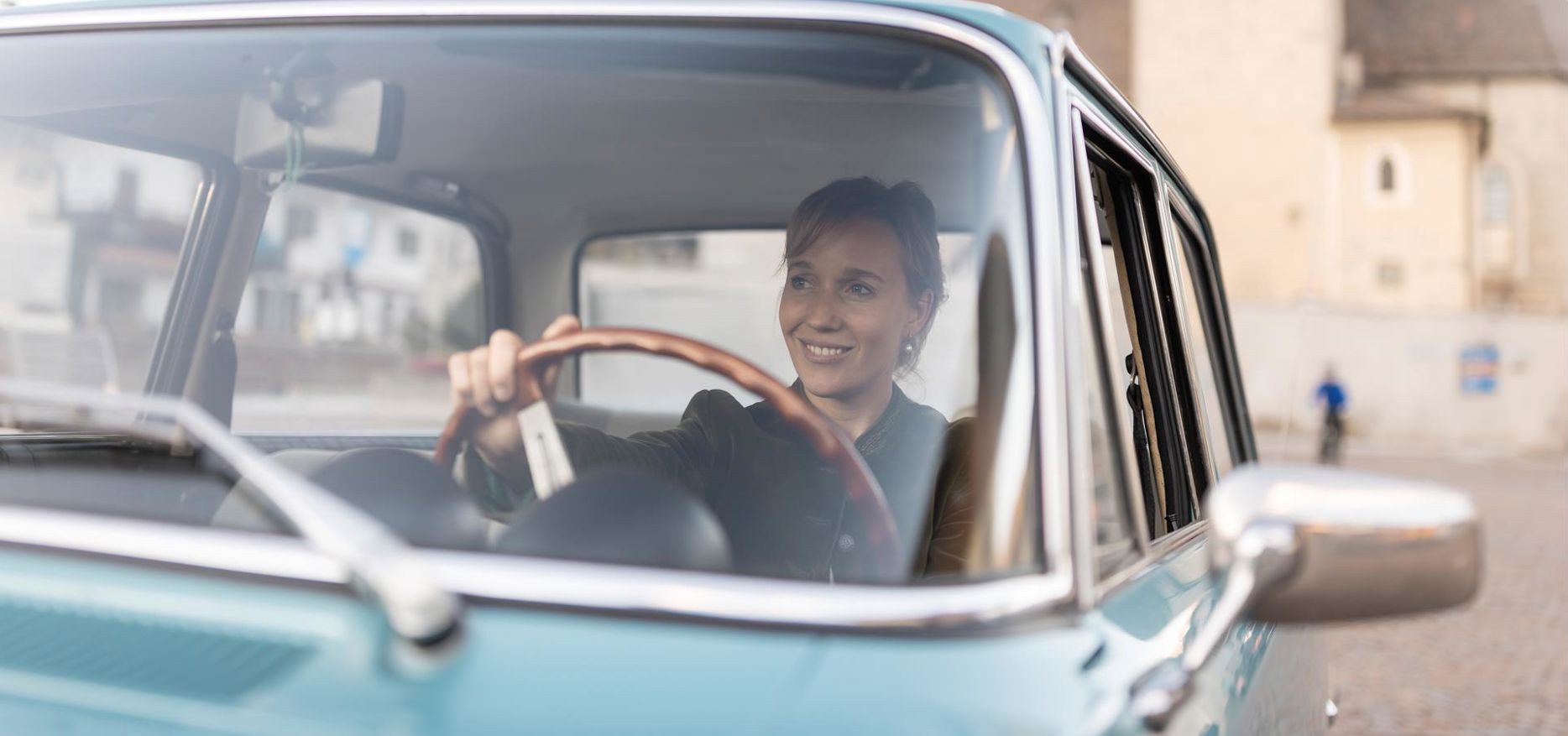 A woman is sitting in a vintage car